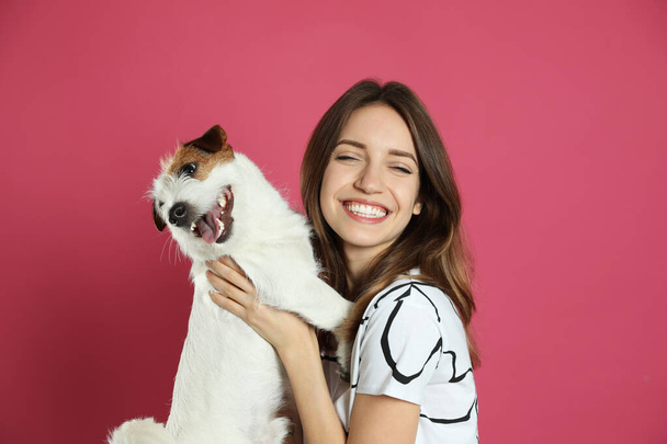 Young woman with her cute Jack Russell Terrier on pink background. Lovely pet - Foto, immagini