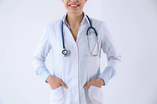 Young doctor with stethoscope on white background, closeup - Foto, afbeelding