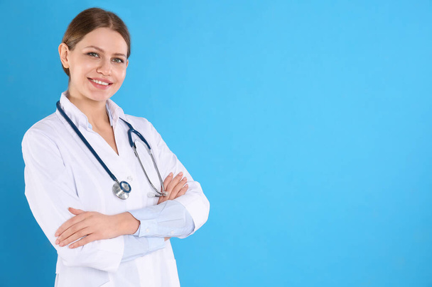 Portrait of young doctor with stethoscope on blue background, space for text - Foto, Bild