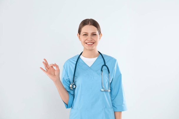 Young doctor with stethoscope against light background - Photo, Image