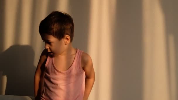 Shot Video Junge gegen die weiße Wand schielt von der hellen Sonne - Filmmaterial, Video