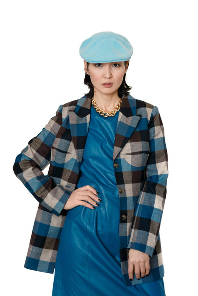 Young woman of oriental nationality in a checkered jacket and blue beret on a white background, posing in front of the camera - Valokuva, kuva