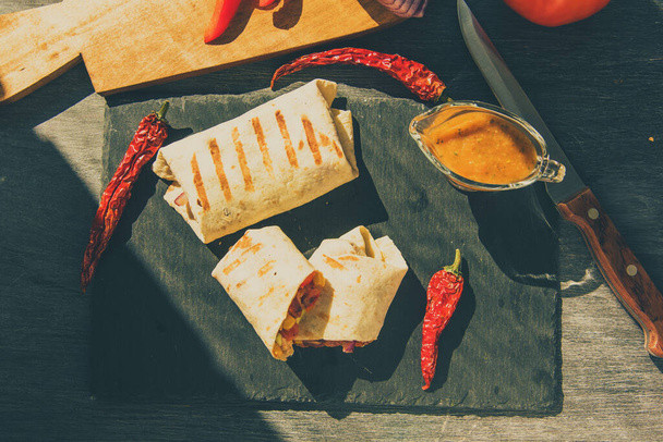 Burrito vegetariano mexicano tradicional en una tabla de servir de cerca, vista superior
 - Foto, imagen