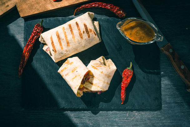 Burrito vegetariano mexicano tradicional en una tabla de servir de cerca, vista superior
 - Foto, Imagen