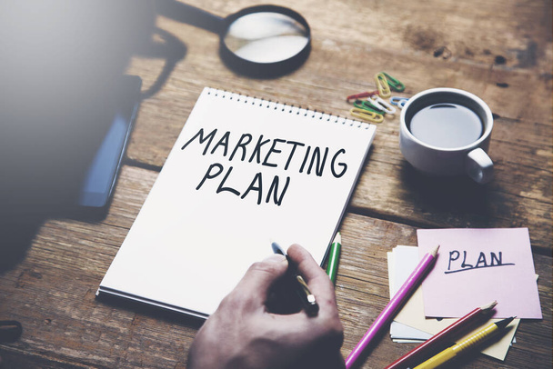 man written marketing plan on notepad with stationary on table - Foto, imagen