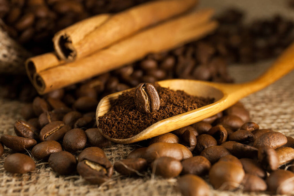 クローズアップ、挽いたコーヒーとコーヒー豆の木のスクープ、バラップのテクスチャの背景にシナモンスティック - 写真・画像