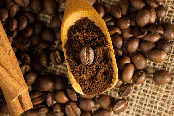 クローズアップ、挽いたコーヒーとコーヒー豆の木のスクープ、バラップのテクスチャの背景にシナモンスティック - 写真・画像