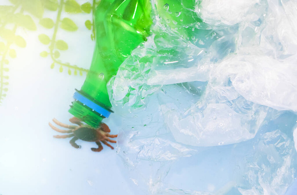 Plastik bir torbaya dolanmış küçük bir yengeç. Okyanusların plastik kirliliği yüzünden. Ekoloji ve çevre koruma kavramı - Fotoğraf, Görsel