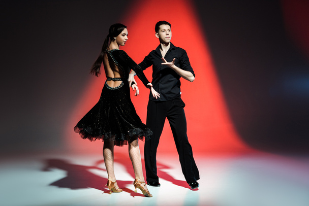 elegant young couple of ballroom dancers dancing in red light - Photo, Image