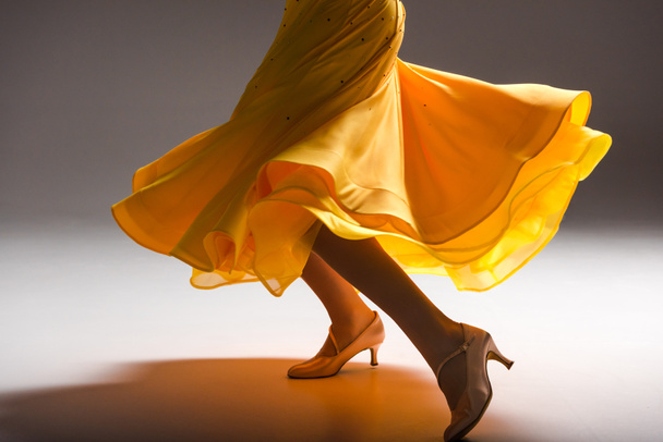 περικοπή άποψη της κομψής νεαρή χορεύτρια αίθουσα χορού σε κίτρινο φόρεμα χορό στο σκοτάδι - Φωτογραφία, εικόνα