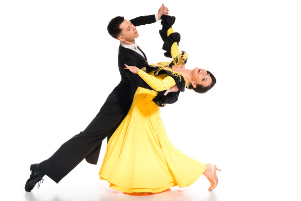 elegant young couple of ballroom dancers in yellow dress and black suit dancing on white - Photo, Image