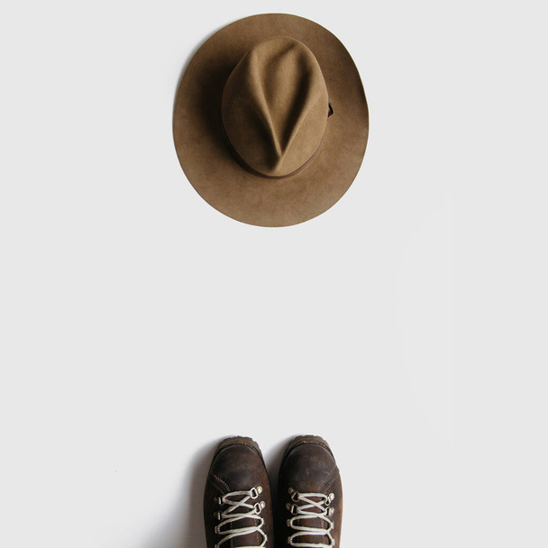 Vintage caminhadas botas e chapéu flatlay no fundo branco isolado. Conceito de viagem mochila minimalista. Espaço vazio, espaço para texto
.  - Foto, Imagem
