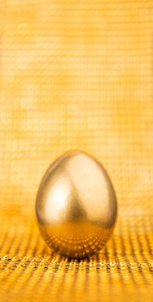 Ενιαία λαμπερό χρυσό βαμμένο αυγό σε κίτρινο λαμπερό φόντο. Μοντέρνο δημιουργικό μινιμαλιστικό στυλ Πάσχα έννοια διακοπών. Κενός χώρος, χώρος για κείμενο, αντίγραφο. - Φωτογραφία, εικόνα