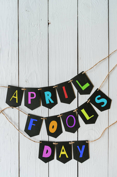April fools day black banner colorful lettering on white barn wood rustic planks background. Greeting postcard template. Space for text, copy. - Photo, Image