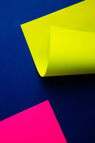 Vibrant neon pink and folded toxic acid green color paper on dark blue background. Abstract geometric diagonal trendy pattern design. Analog minimalist electronic party vibe. - Photo, Image