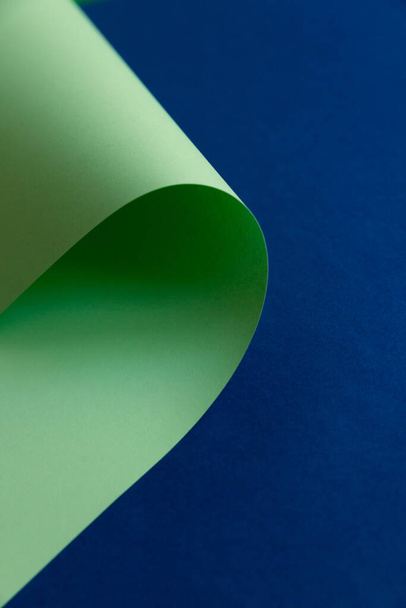 薄緑色のツイスト、濃紺の背景にネオミントカラーの紙。抽象的なファッション曲線シームレスな創造的な背景。コピー、テキスト、レタリングのための空のスペース. - 写真・画像