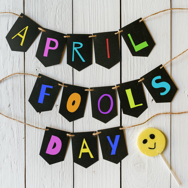 April fools day black banner colorful lettering on white barn wood rustic planks background. Holiday greeting postcard. - Zdjęcie, obraz