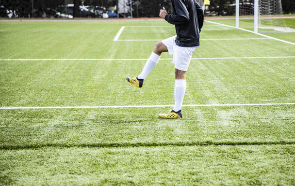 nuori ja tunnistamaton jalkapalloilija lämpenee mennä ulos pelaamaan
 - Valokuva, kuva