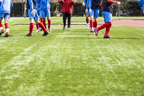 Young and unrecognizable soccer team doing training exercises with their coach, unfocused view. - Foto, immagini