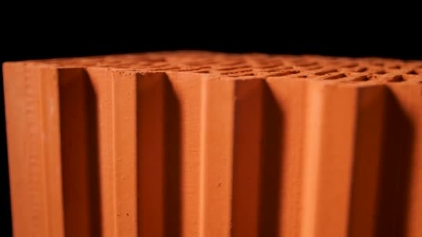 Close-up van geperforeerde keramische blokken met ronde gaten geïsoleerd op zwarte achtergrond. Voorraadbeelden. Materialen voor de bouw van een nieuw stenen huis. - Video