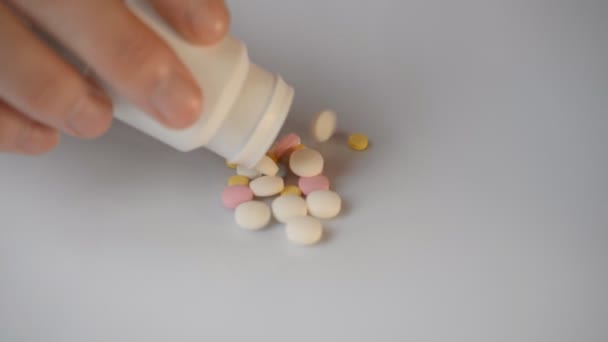 colored pills to lower the temperature and treat flu get enough sleep from a white bottle on a white background - Felvétel, videó