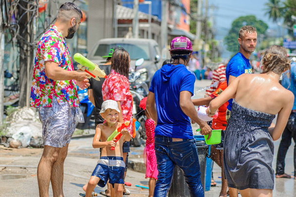 Thais und Touristen schießen mit Wasserpistolen, übergießen sich mit Wasser und amüsieren sich beim Songkran-Fest, dem traditionellen thailändischen Neujahrsfest - Foto, Bild