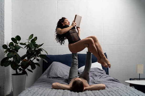 Couple spending time together reading book and making acrobatic balance at home. concept of self-development and creativity. - Φωτογραφία, εικόνα
