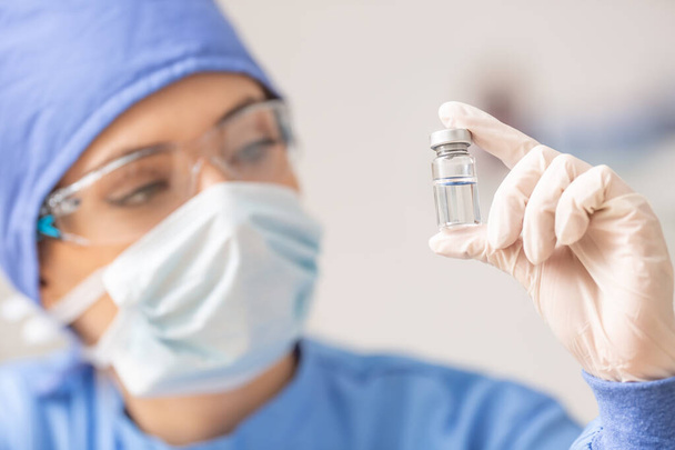 Female laboratory technician with ampoule of virus vaccine. - Φωτογραφία, εικόνα