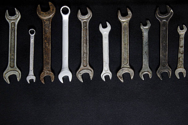 Un conjunto de herramientas de reparación en una caja de cuero sobre un fondo negro. Llaves de diferentes tamaños
 - Foto, imagen