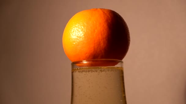 Mandarin rests on a glass of foaming champagne - Filmagem, Vídeo