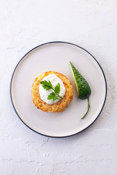 potato pancakes with sour cream , fresh cucumber and herbs on a white plate and a white background - Foto, Imagem