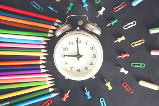 colorful pencils with clock and stationary on desk - Фото, зображення
