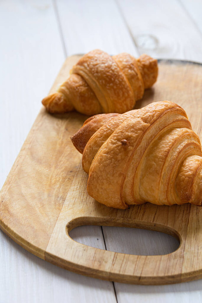 two croissants on a wooden board on a white table - Photo, Image