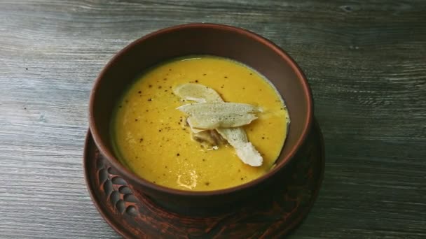 zoom out from yellow cream soup trendy decorated with mushrooms and dried bread - Footage, Video