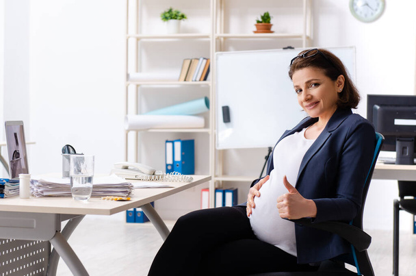 Vieja embarazada trabajando en la oficina - Foto, imagen
