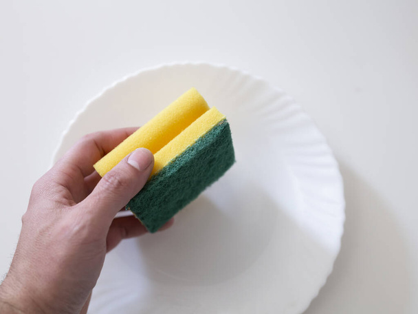 hand with scourer to clean plate - Photo, Image
