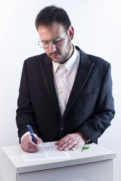man with glasses in a black suit, signing mortgage papers, white background, financial concept - 写真・画像