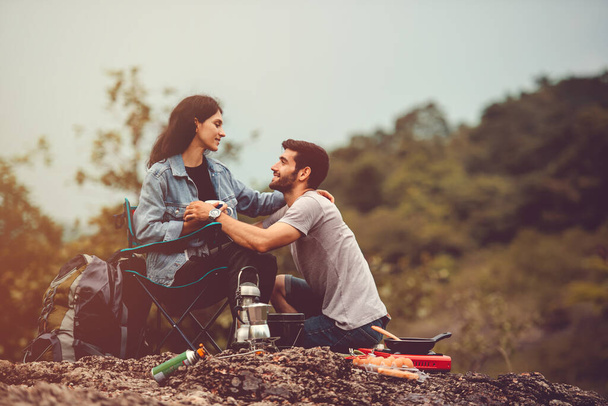 幸せなカップルは朝のキャンプ場でキャンプテントの前で料理を楽しむ - 写真・画像