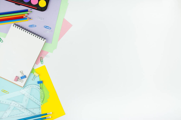 School supplies on a white background. Multicolored wooden pencils, notebook, paper clips, rulers, paper stickers. Office tools. Education concept copy space - Photo, image