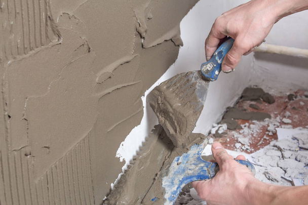 Repair the wall. Plastering the wall.Hand holding a spatula with construction mix.Applying putty or tile glue to the wall.Plaster the wall with a putty knife.Internal construction and finishing works - Photo, Image