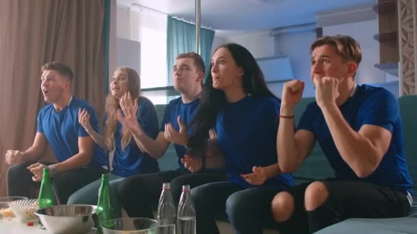 Gruppe gut gelaunter Freunde schaut Fußballspiel und feiert Sieg zu Hause - Filmmaterial, Video