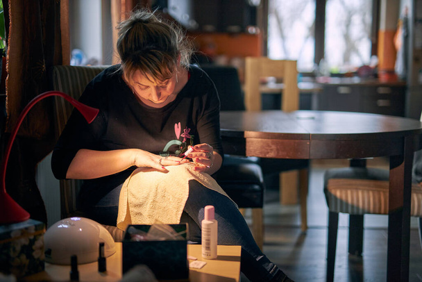 Woman doing manicure at home. Panting fingernails with hybrid nail polish. Woman using UV Led nail lamp to manicure - Photo, Image