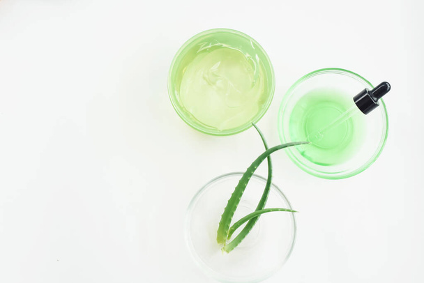 Aloe gel, plant leaves and green serum from natural extracts on a white background. Moisturizing the skin with aloe gel. Flat lay, pattern. - Foto, imagen