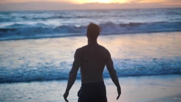 Silhueta de um homem musculoso levanta as mãos e meditação sobre o pôr do sol mar no fundo
. - Filmagem, Vídeo