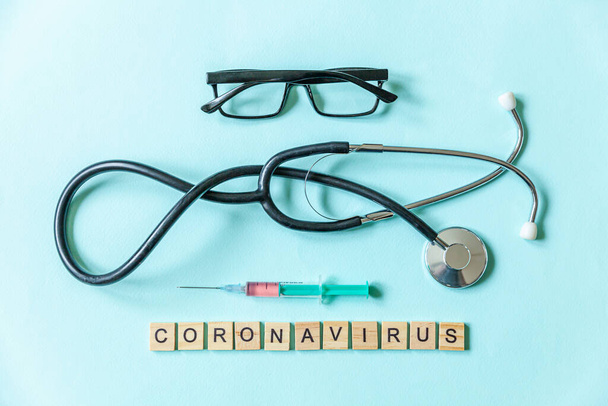 Teksti lause Coronavirus ruiskun silmälasit ja stetoskooppi sininen pastelli tausta. Novel coronavirus 2019-nCoV, MERS-Cov Lähi-idän hengitystieoireyhtymä Wuhan, Kiina
 - Valokuva, kuva