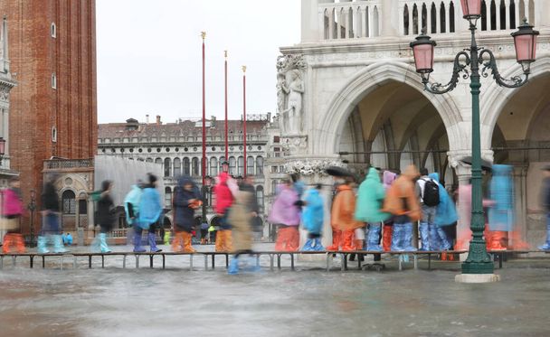 veel mensen lopen op een catwalk in Venetië vanwege het hoogwater - Foto, afbeelding
