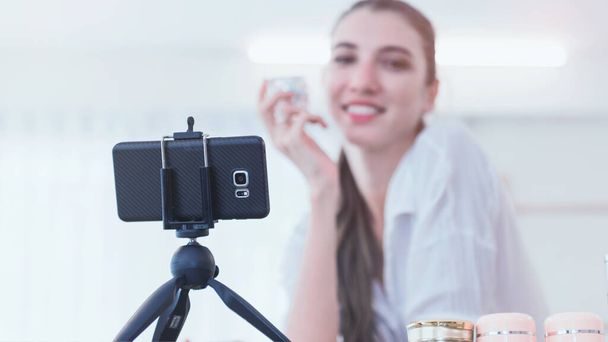 Hermosa mujer blogger belleza grabación en vivo maquillaje tutorial compartir en las redes sociales utilizando la cámara digital en el trípode
. - Foto, imagen