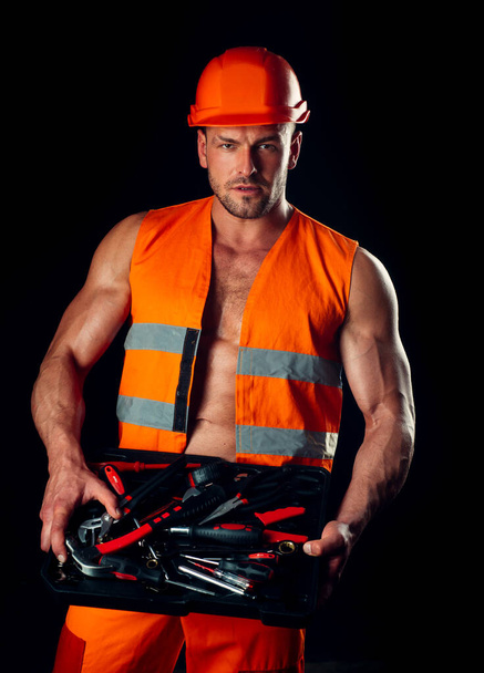 Portrait of male factory worker. Portrait of handsome repairman holding wrench over black background. - Fotó, kép