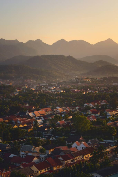 Elevated view of the city of Luang Prabang, Laos, at sunset, with mountains on the background. - Fotó, kép