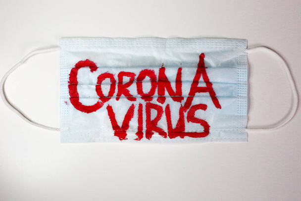 Surgical face mask with coronavirus text written on it.  - 写真・画像